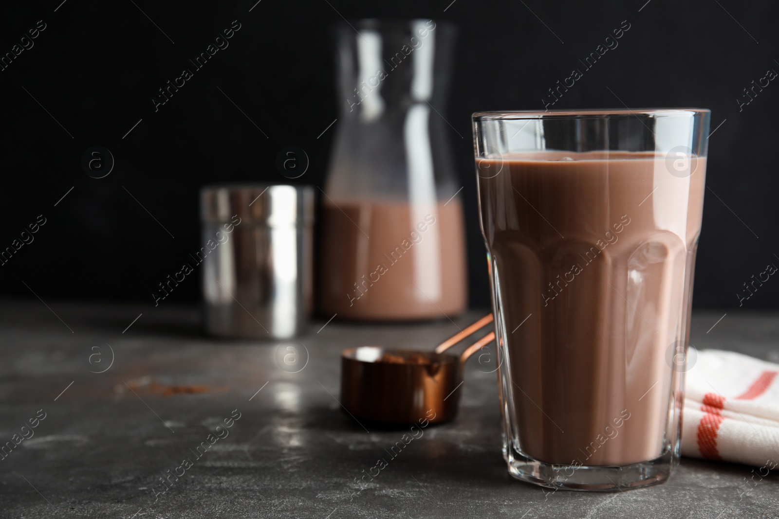 Photo of Glass with tasty chocolate milk on gray table, space for text. Dairy drink