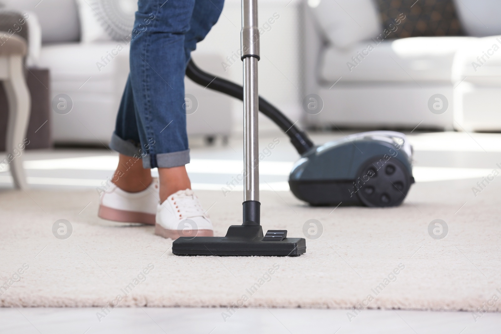 Photo of Woman cleaning carpet with vacuum cleaner, closeup