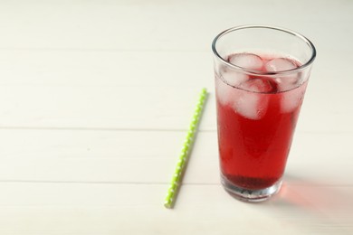 Photo of Refreshing hibiscus tea with ice cubes in glass and straw on white wooden table. Space for text