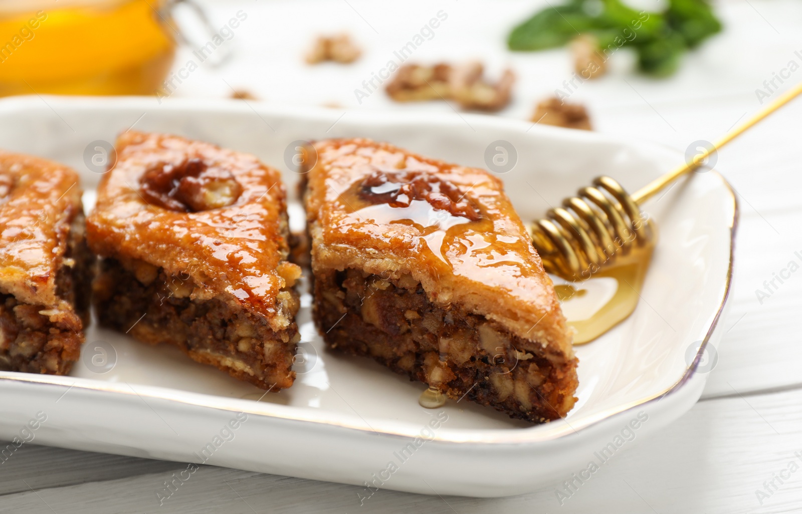 Photo of Delicious sweet baklava with walnuts on white wooden table, closeup