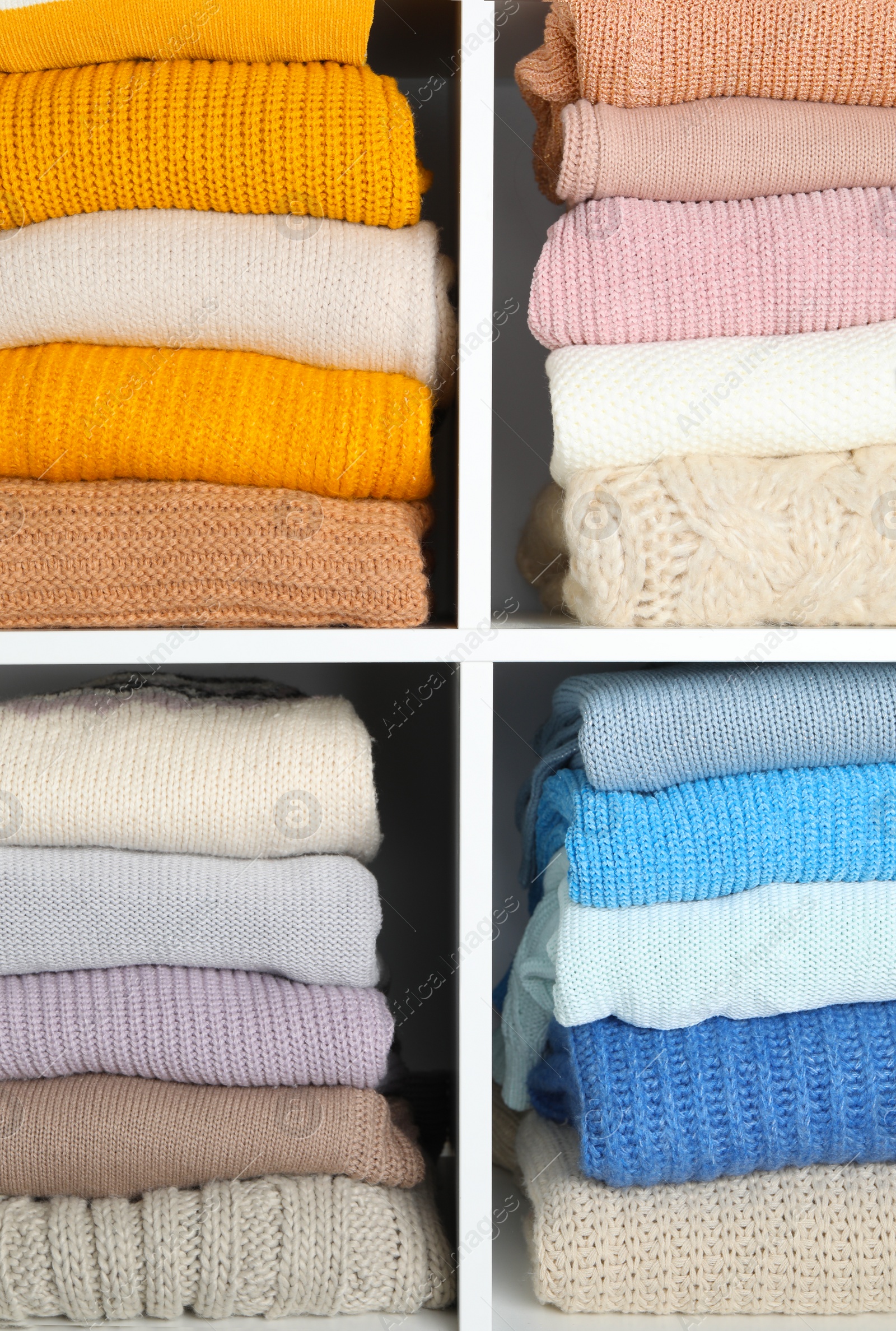 Photo of Many knitted winter clothes stacked on shelves