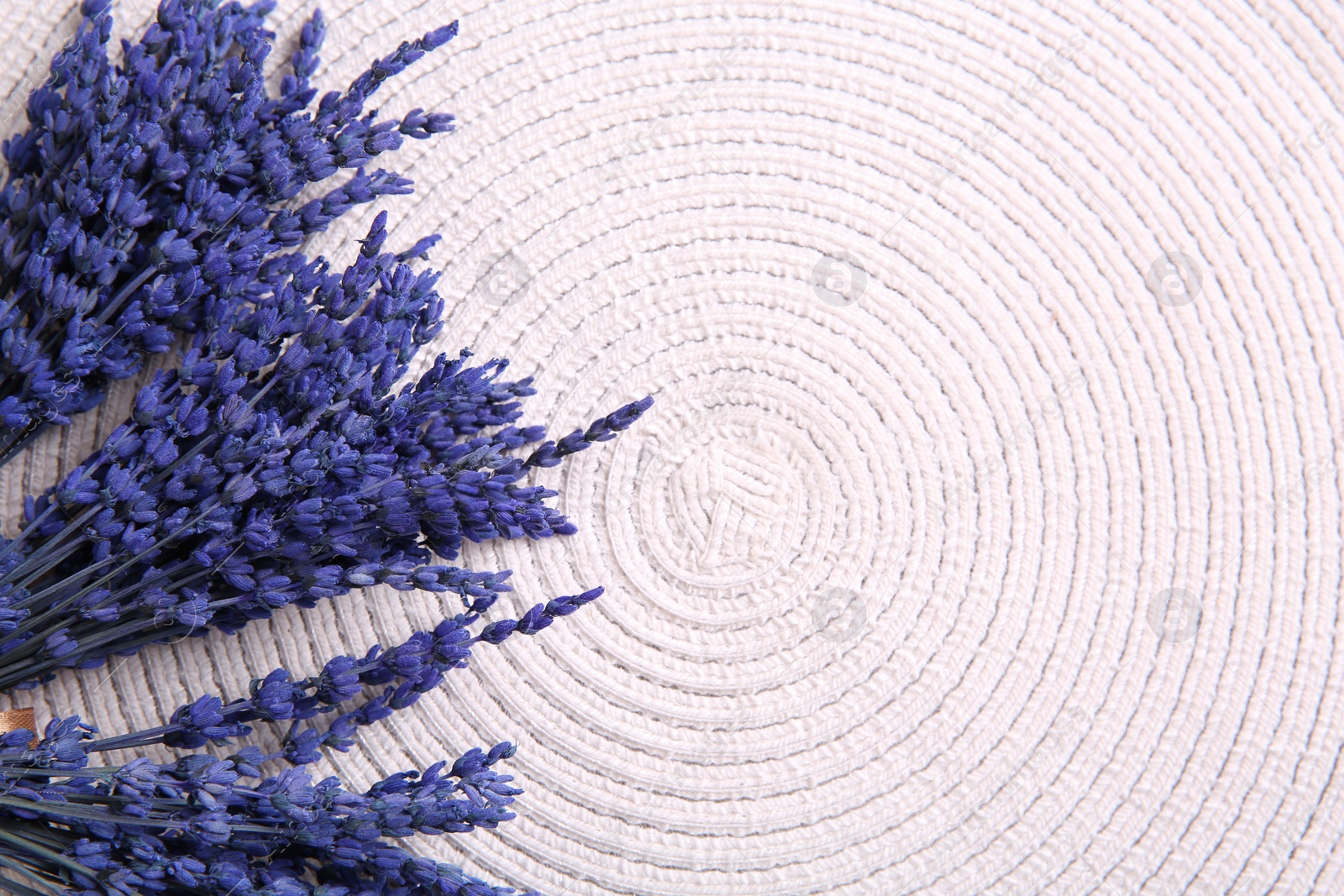 Photo of Bouquets of beautiful preserved lavender flowers on white cotton place mat, top view. Space for text