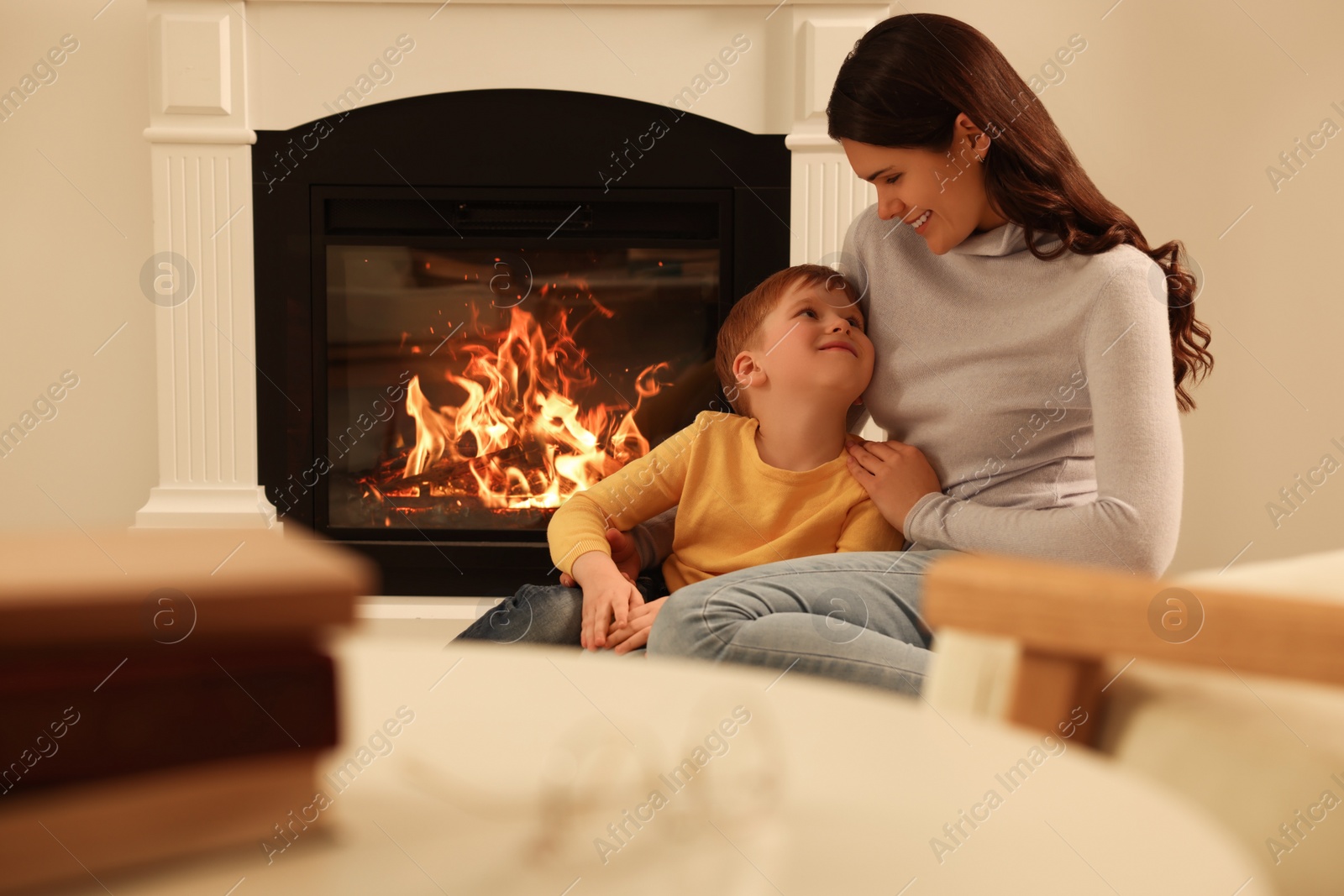 Photo of Happy mother and son spending time together near fireplace at home