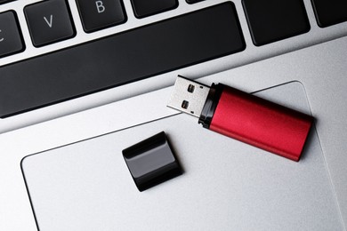 Photo of Modern usb flash drive on laptop, top view