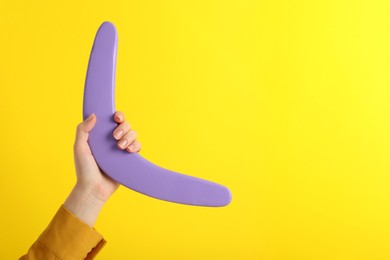 Photo of Woman holding boomerang on yellow background, closeup. Space for text