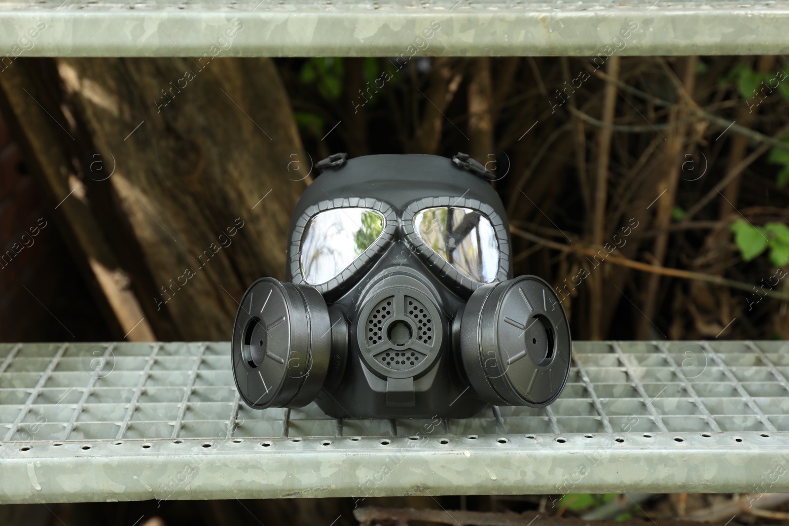 Photo of One gas mask on stairs outdoors. Safety equipment