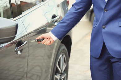 Closeup view of man opening car door with key