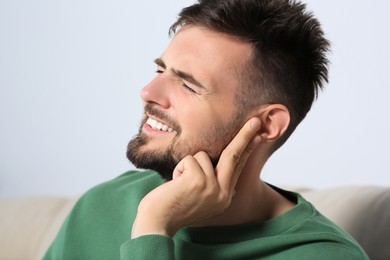 Photo of Young man suffering from ear pain at home