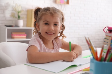 Photo of Cute little girl doing homework at table
