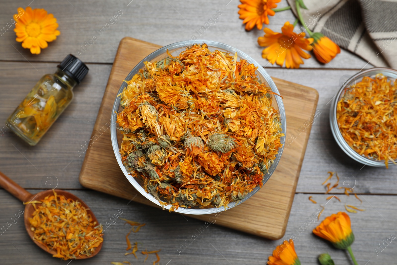 Photo of Dry calendula flowers and bottle with tincture on wooden table, flat lay