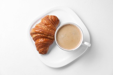 Photo of Fresh croissant and coffee on white background, top view. Tasty breakfast