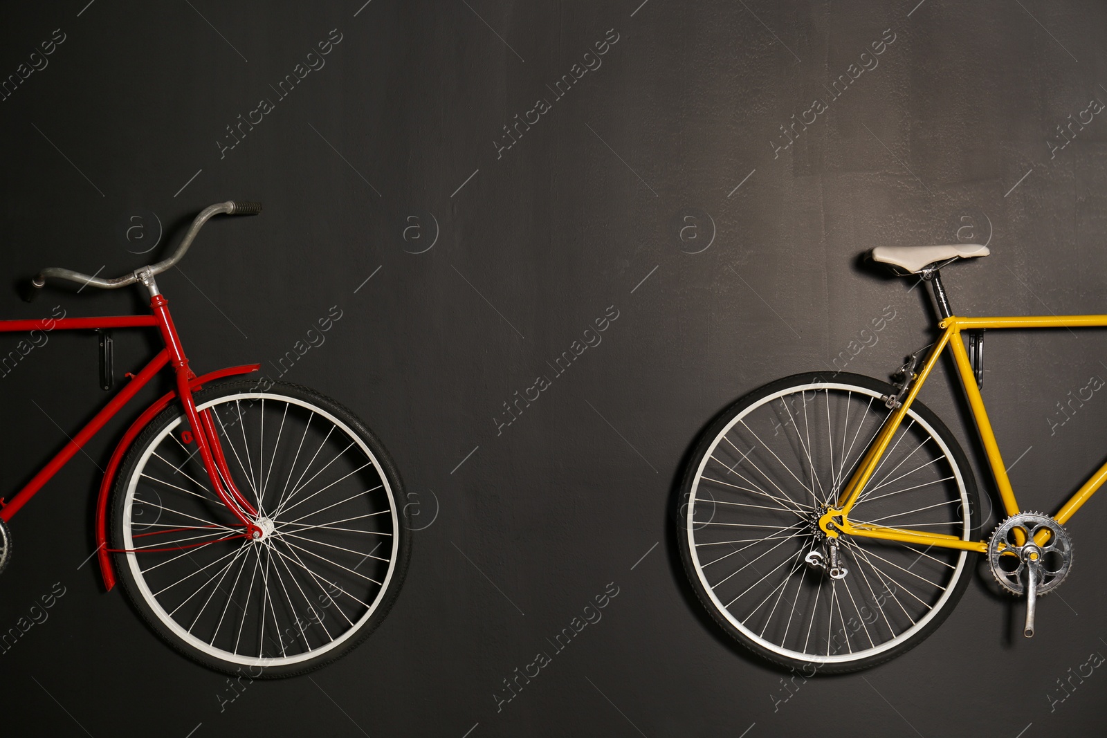 Photo of Color bicycles hanging on black wall indoors