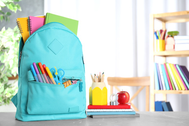 Photo of Stylish backpack with different school stationery on table indoors. Space for text