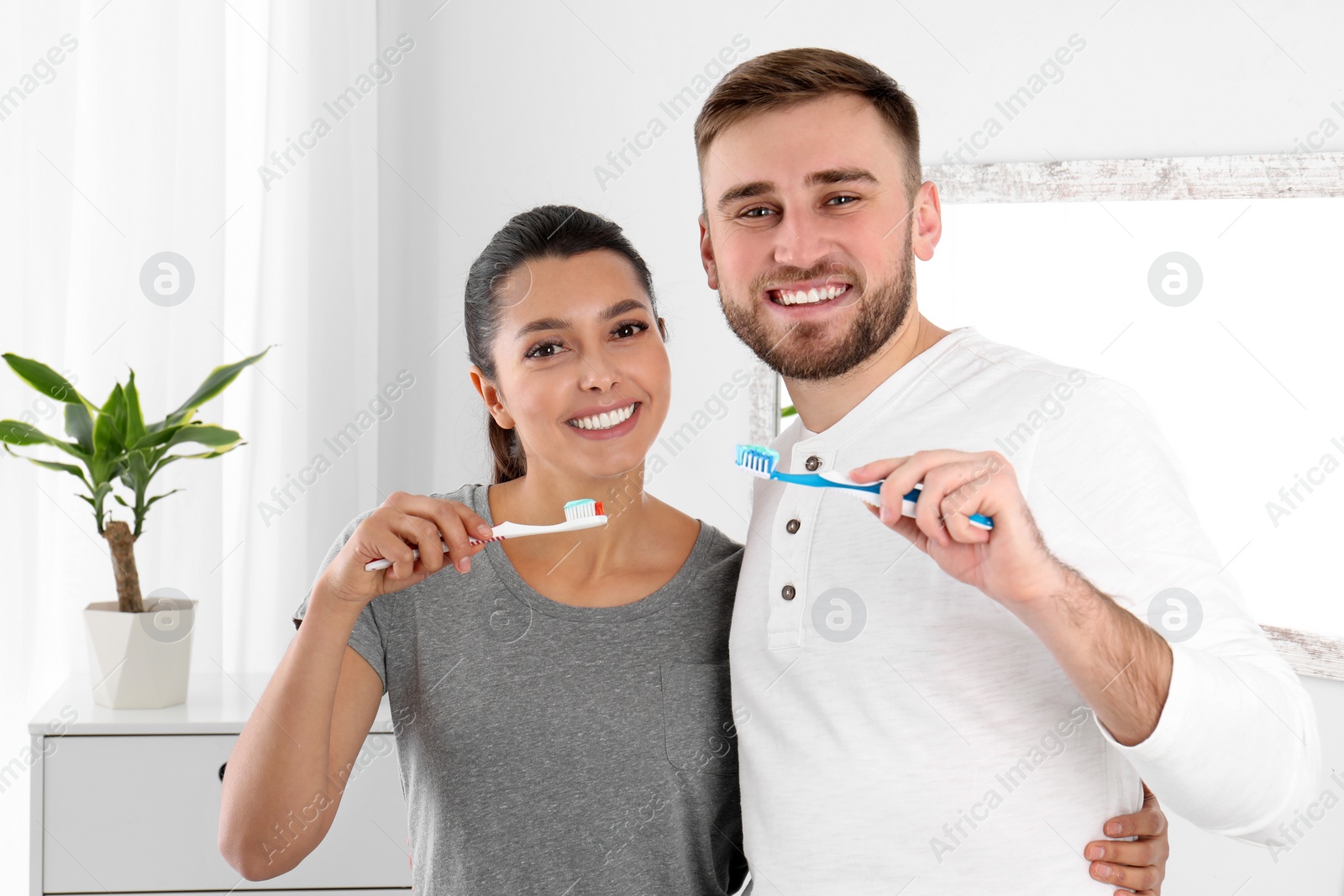 Photo of Young couple with toothbrushes in bathroom. Teeth care