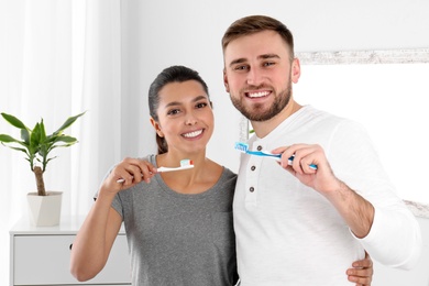 Photo of Young couple with toothbrushes in bathroom. Teeth care
