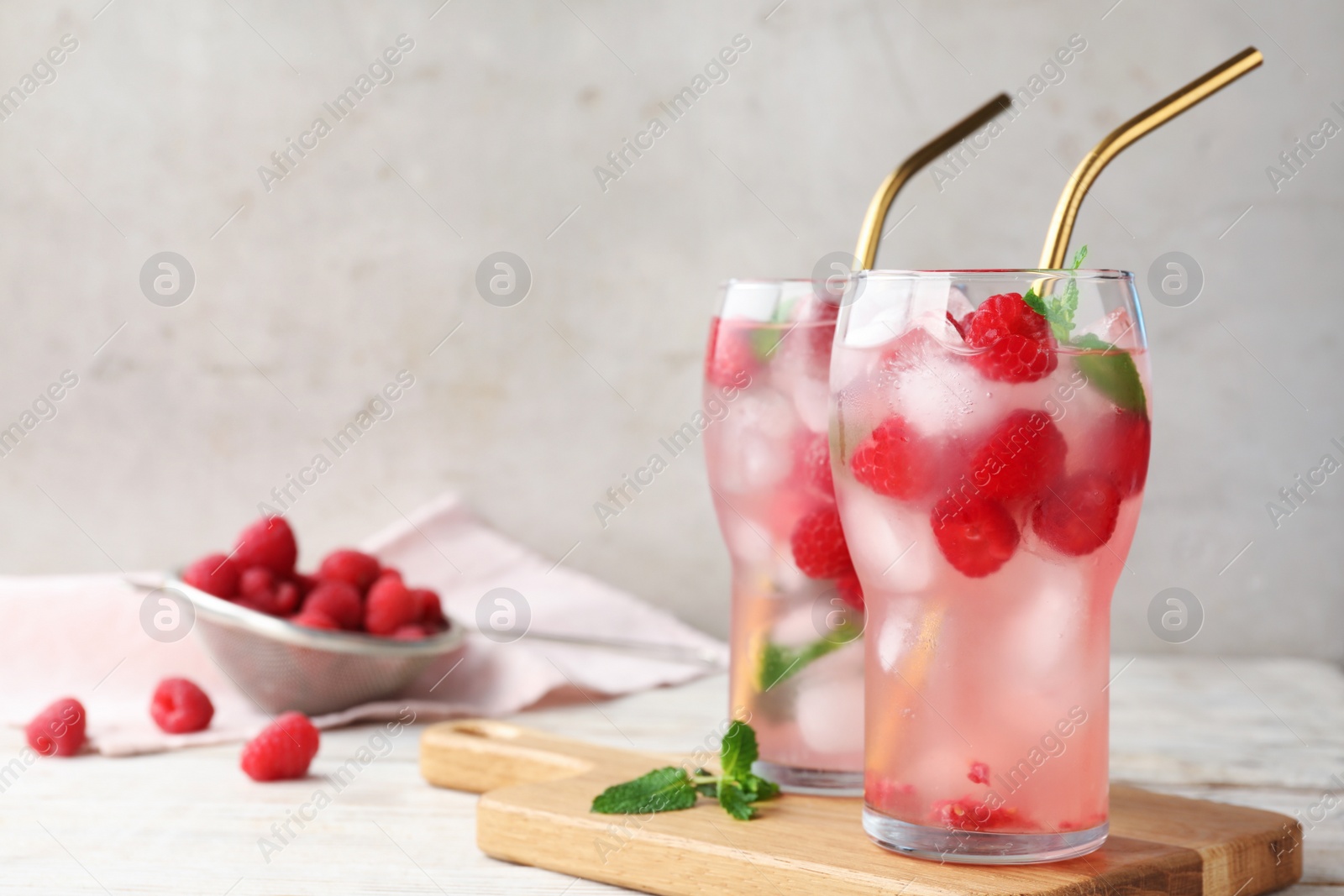 Photo of Glasses of refreshing drink with raspberry and mint on white wooden table against grey background, space for text