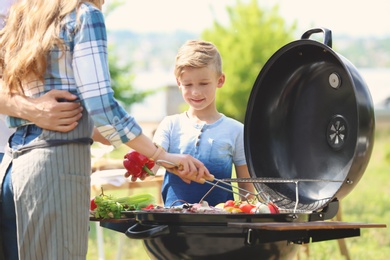 Photo of Happy family having barbecue with modern grill outdoors