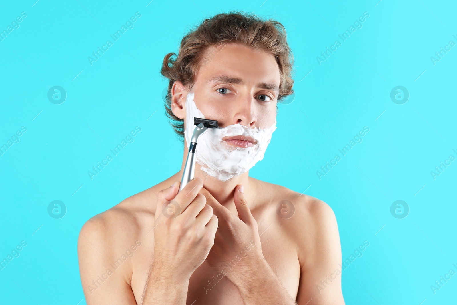 Photo of Handsome young man shaving on color background