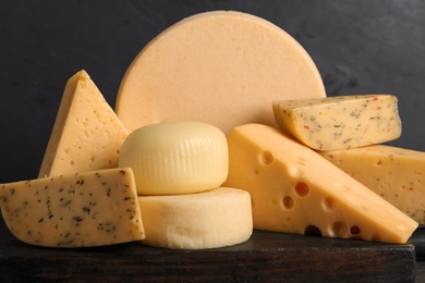 Wooden board with different sorts of cheese on grey background