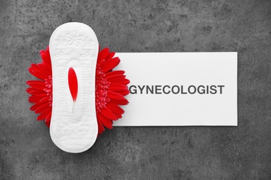 Flat lay composition with menstrual pad and red flower on grey background. Gynecological care