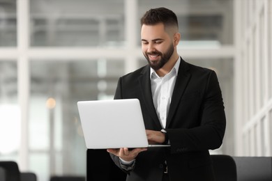 Smiling man working with laptop in office, space for text. Lawyer, businessman, accountant or manager