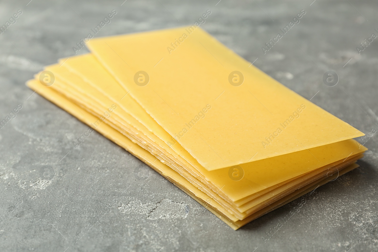 Photo of Uncooked lasagna sheets on dark table, closeup