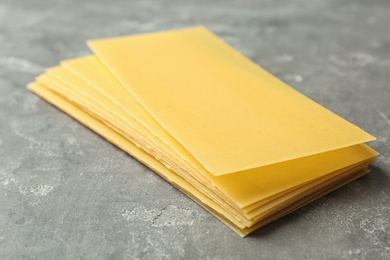 Photo of Uncooked lasagna sheets on dark table, closeup