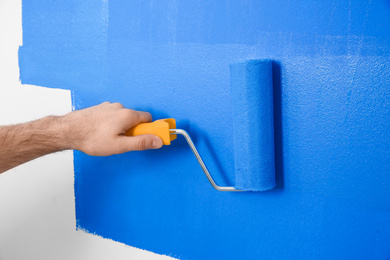 Photo of Man painting white wall with blue dye, closeup. Interior renovation