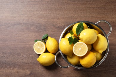 Photo of Fresh lemons and green leaves on wooden table, top view. Space for text