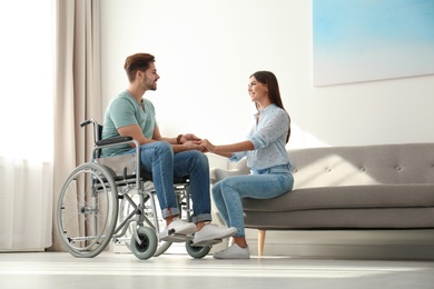 Photo of Young woman with man in wheelchair indoors