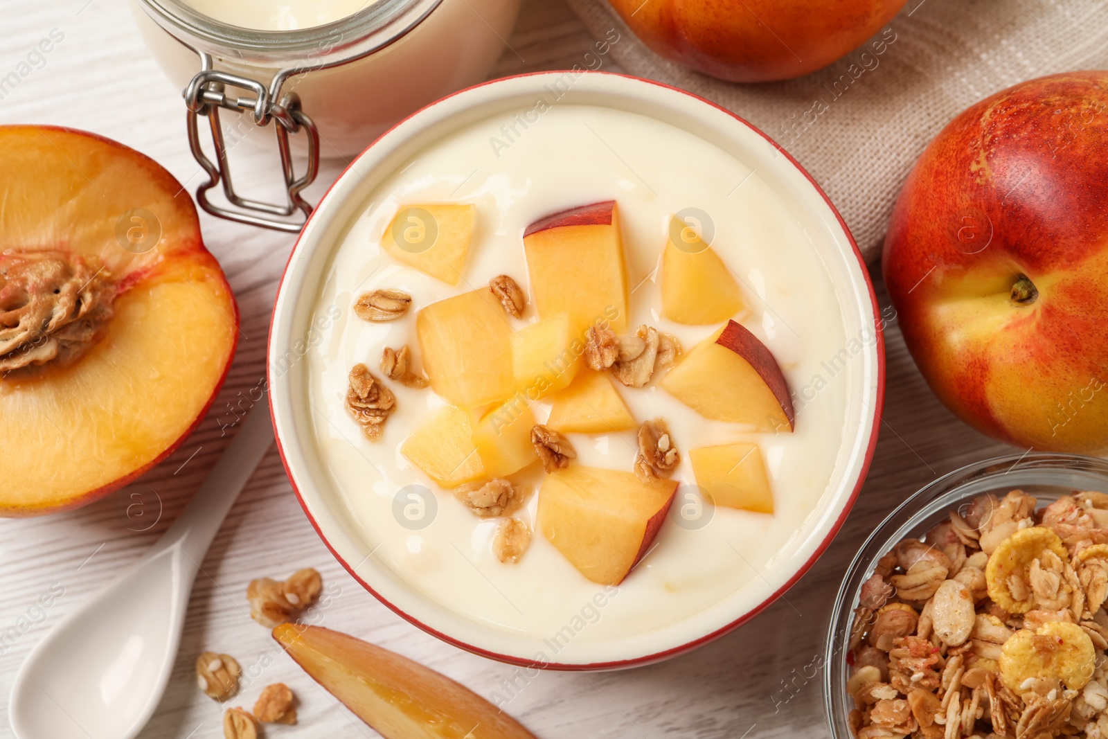 Photo of Delicious yogurt with fresh peach and granola on white wooden table, flat lay