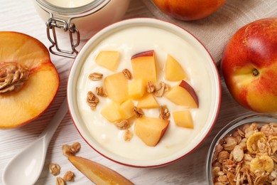 Photo of Delicious yogurt with fresh peach and granola on white wooden table, flat lay