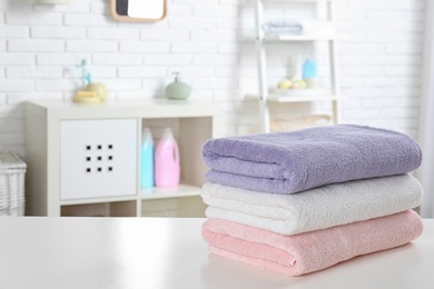 Photo of Stack of fresh towels on table in bathroom. Space for text