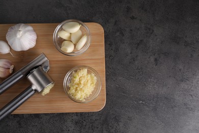 Garlic press, cloves and mince on wooden table, top view. Space for text