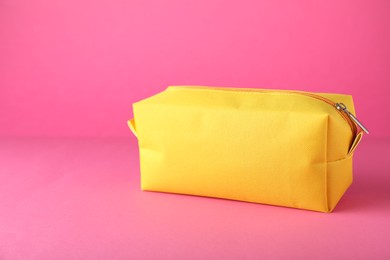 Yellow cosmetic bag on pink background. Space for text