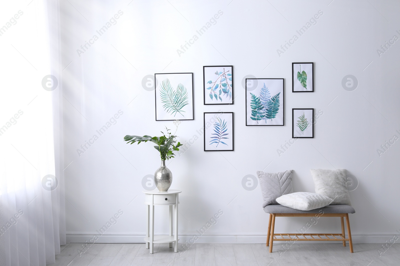 Photo of Beautiful paintings of tropical leaves on white wall in living room interior