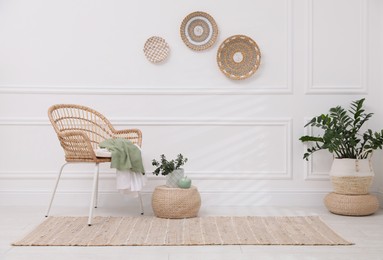 Photo of Stylish room interior with beige rug, wicker armchair and plants