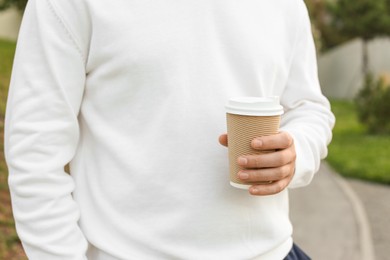 Coffee to go. Man with paper cup of drink outdoors, closeup