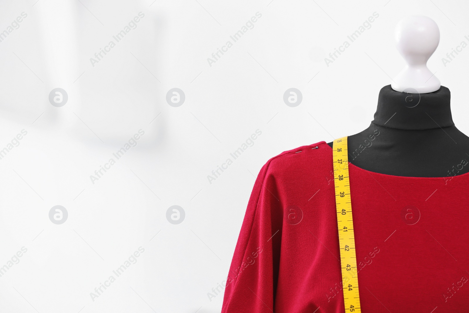 Photo of Mannequin with dress and measuring tape in tailor studio, closeup