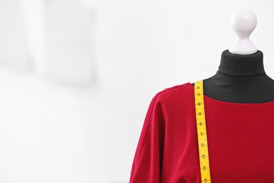 Mannequin with dress and measuring tape in tailor studio, closeup