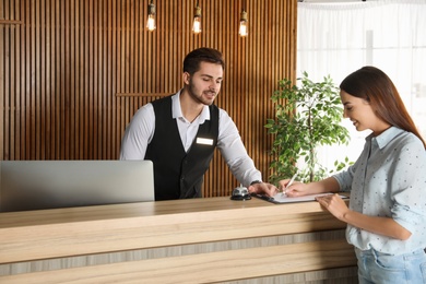 Photo of Receptionist registering client at desk in lobby