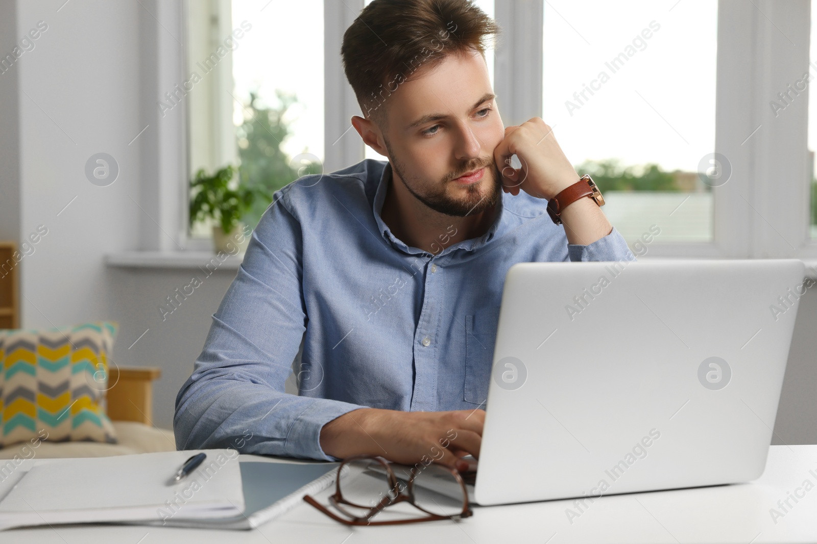 Photo of Handsome man working with laptop at table indoors