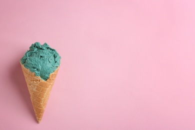 Photo of Delicious spirulina ice cream cone on color background, top view. Space for text