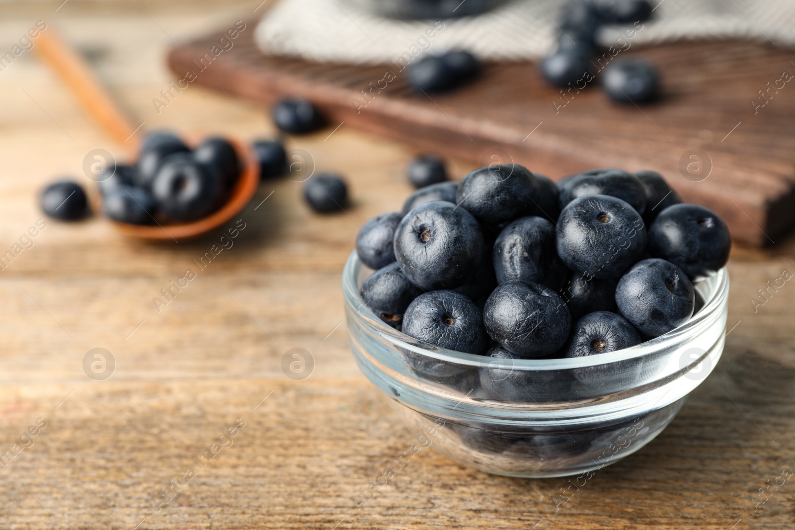 Photo of Bowl of fresh acai berries on wooden table, closeup. Space for text