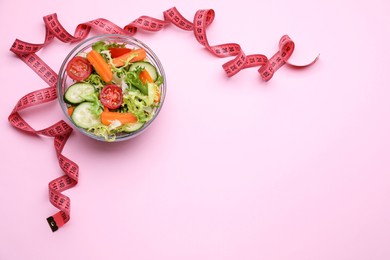 Photo of Measuring tape and salad on pink background, flat lay. Space for text