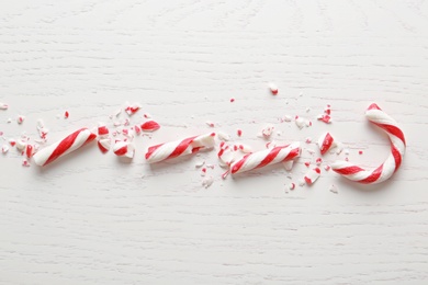 Photo of Crushed candy cane on white wooden background, flat lay. Traditional Christmas treat