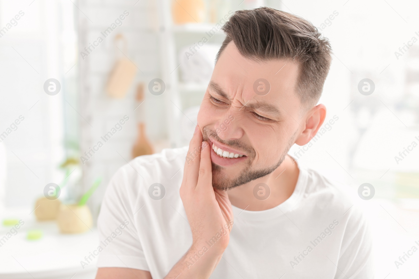 Photo of Young man suffering from toothache indoors