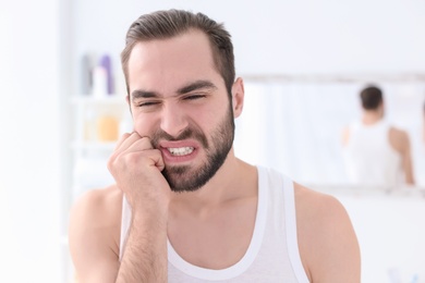 Young man suffering from toothache indoors