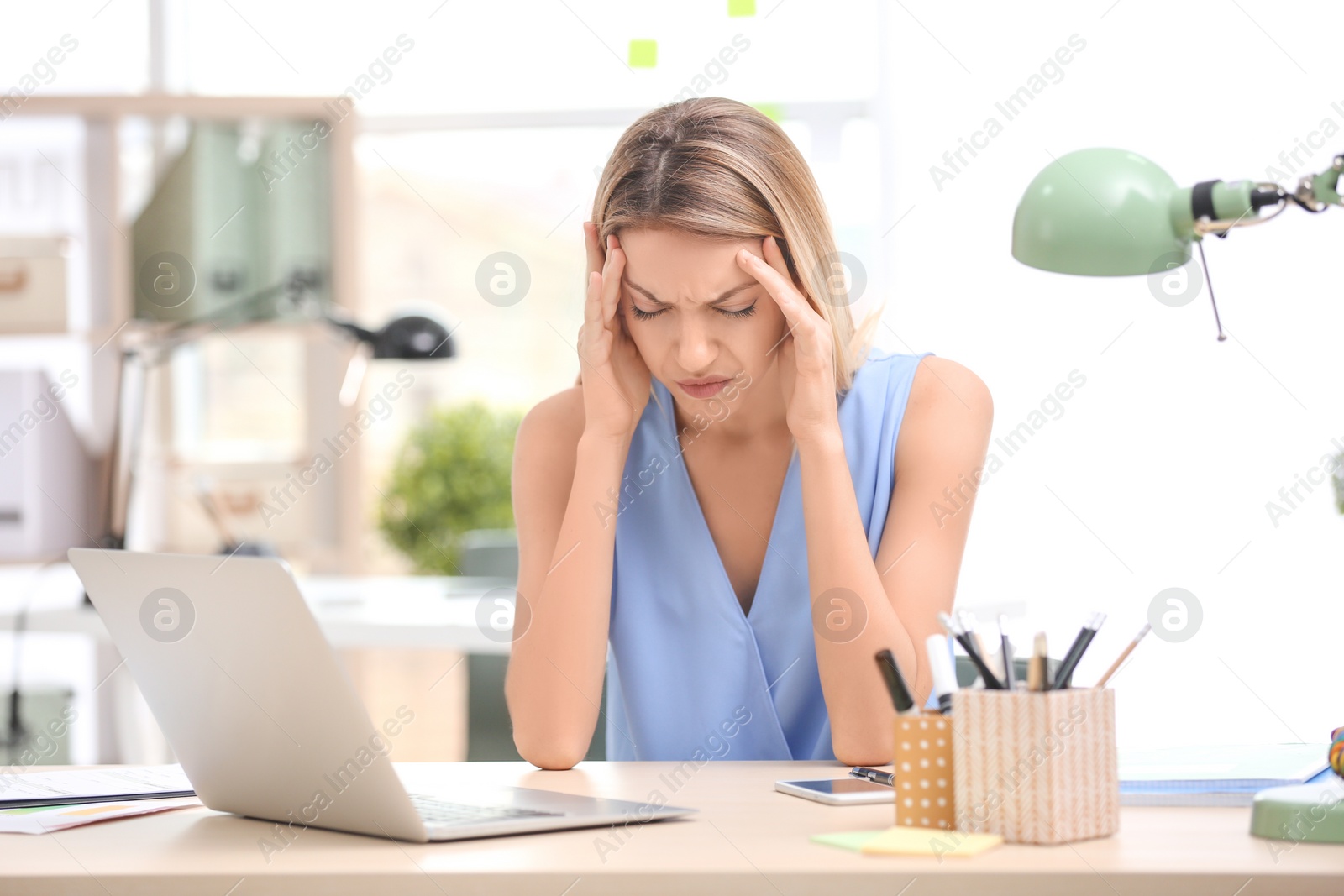 Photo of Young woman suffering from headache in office