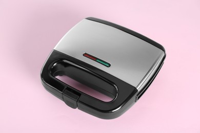 Photo of Modern sandwich maker on pink background. Cooking appliance